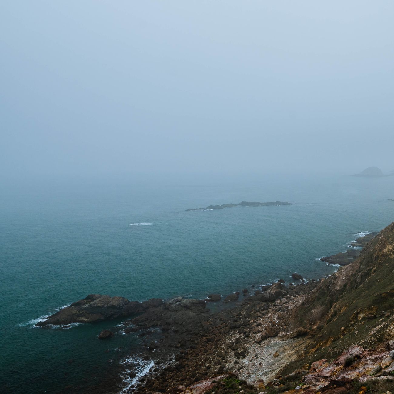 Tranquil coastal cliffside in dramatic morning fog